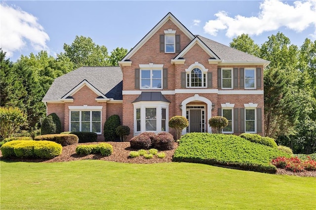 colonial-style house featuring a front lawn and brick siding
