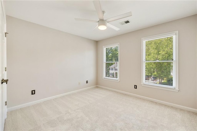 empty room featuring a ceiling fan, baseboards, and light colored carpet