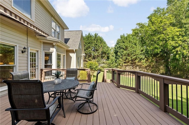 deck featuring outdoor dining space and a lawn