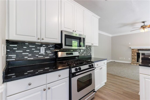 kitchen featuring baseboards, appliances with stainless steel finishes, ceiling fan, backsplash, and white cabinetry