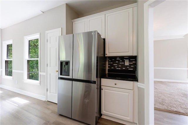 kitchen featuring tasteful backsplash, stainless steel fridge with ice dispenser, dark countertops, white cabinetry, and light wood-type flooring