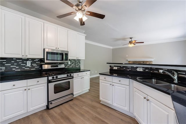 kitchen featuring decorative backsplash, stainless steel appliances, a sink, a ceiling fan, and crown molding