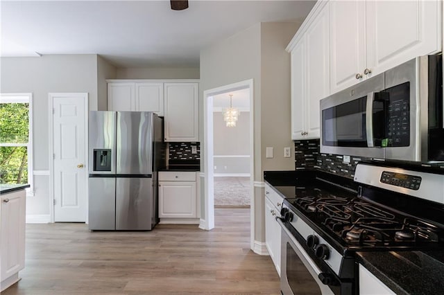 kitchen featuring a chandelier, light wood-type flooring, backsplash, white cabinets, and appliances with stainless steel finishes