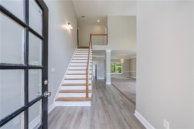 foyer entrance with baseboards, stairway, wood finished floors, and ornate columns