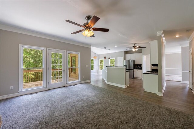 unfurnished living room with crown molding, a ceiling fan, dark colored carpet, and baseboards