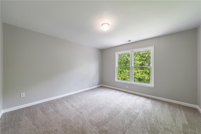empty room featuring visible vents, carpet floors, and baseboards