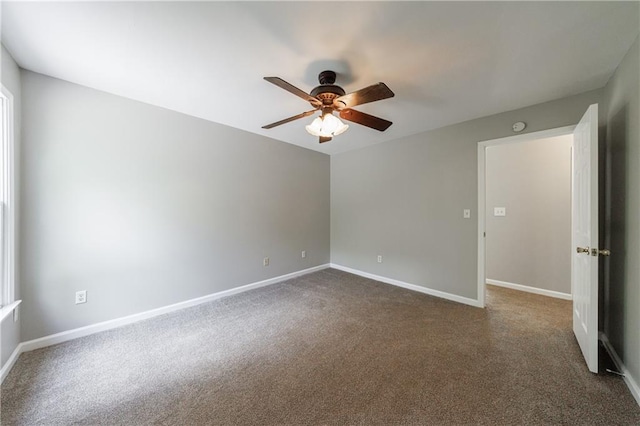 spare room featuring dark carpet, a ceiling fan, and baseboards