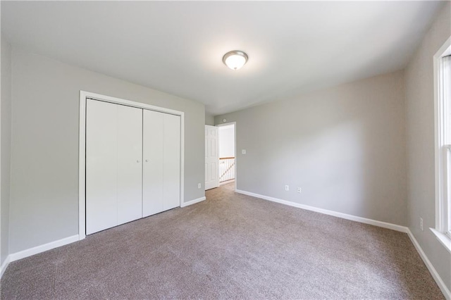 unfurnished bedroom with a closet, carpet flooring, and baseboards