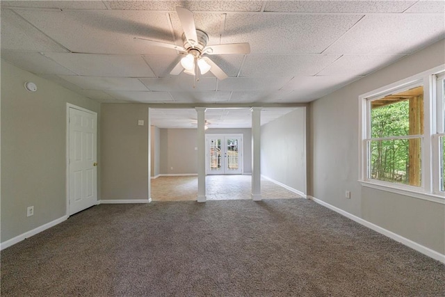 carpeted empty room with plenty of natural light, a paneled ceiling, ceiling fan, and ornate columns