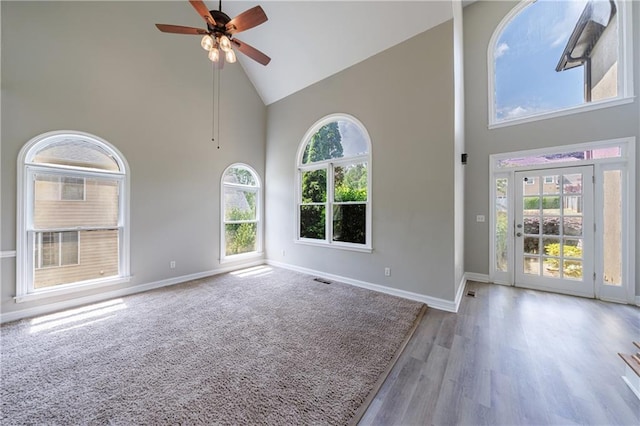 interior space featuring baseboards, high vaulted ceiling, wood finished floors, and ceiling fan