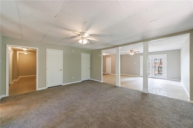 interior space featuring decorative columns, a ceiling fan, carpet, baseboards, and a drop ceiling