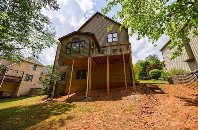 back of property with a deck, fence, and a yard