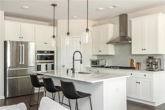 5025 Bryce Ln, Cumming, GA 30040 - kitchen featuring appliances with stainless steel finishes, wall chimney range hood, a sink, backsplash, and white cabinets