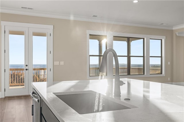 kitchen featuring light wood-type flooring, french doors, ornamental molding, light stone counters, and sink