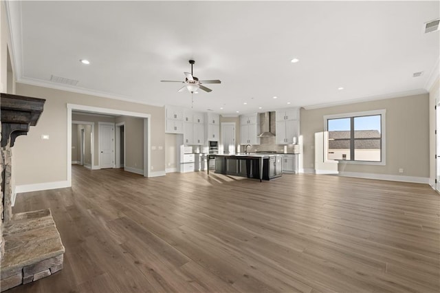 unfurnished living room with crown molding, dark hardwood / wood-style floors, sink, and a stone fireplace