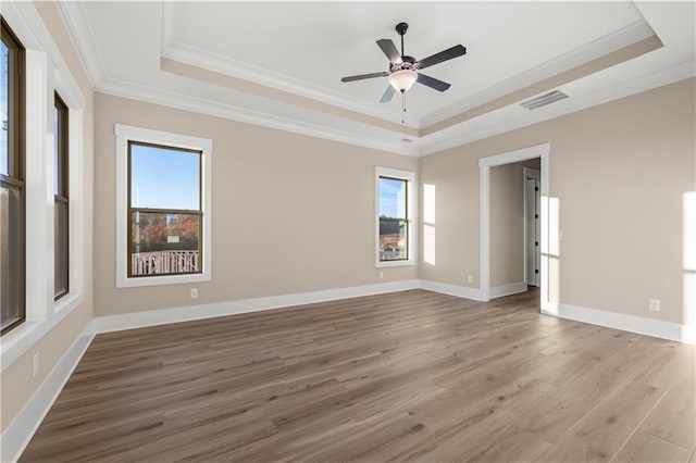 unfurnished room featuring wood-type flooring, a tray ceiling, and ornamental molding