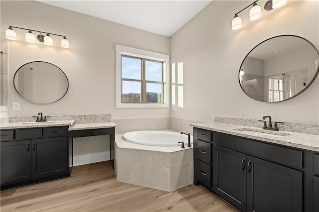 bathroom featuring vanity, a relaxing tiled tub, and hardwood / wood-style flooring