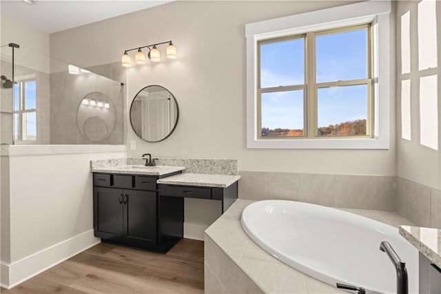 bathroom with hardwood / wood-style flooring, independent shower and bath, plenty of natural light, and vanity