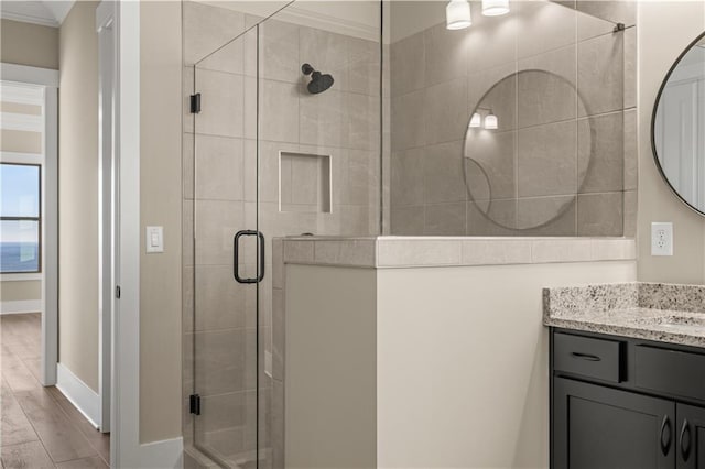 bathroom featuring vanity, a shower with door, crown molding, and hardwood / wood-style floors