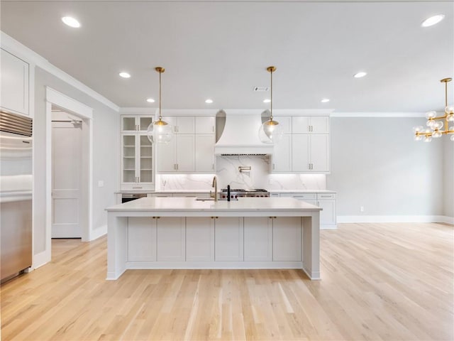 kitchen featuring white cabinetry, hanging light fixtures, and custom range hood