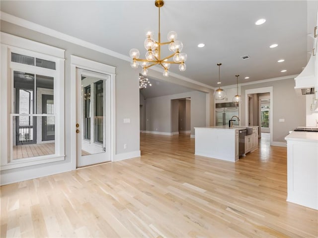 kitchen featuring sink, decorative light fixtures, stainless steel appliances, light hardwood / wood-style floors, and white cabinets