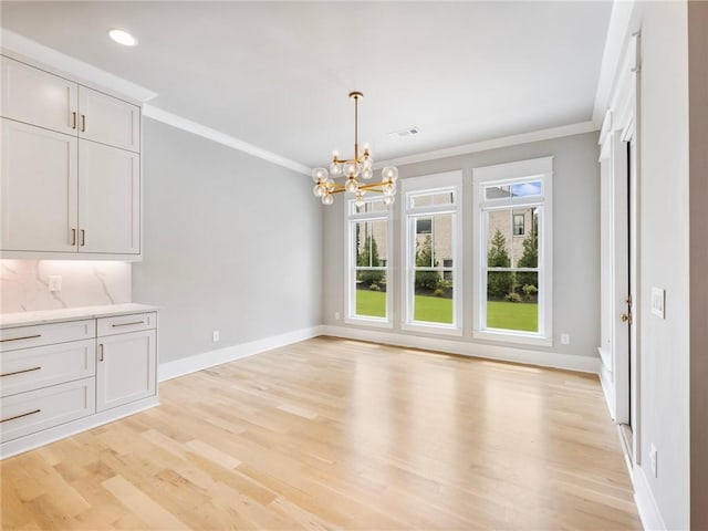 unfurnished dining area featuring a notable chandelier, crown molding, and light hardwood / wood-style flooring