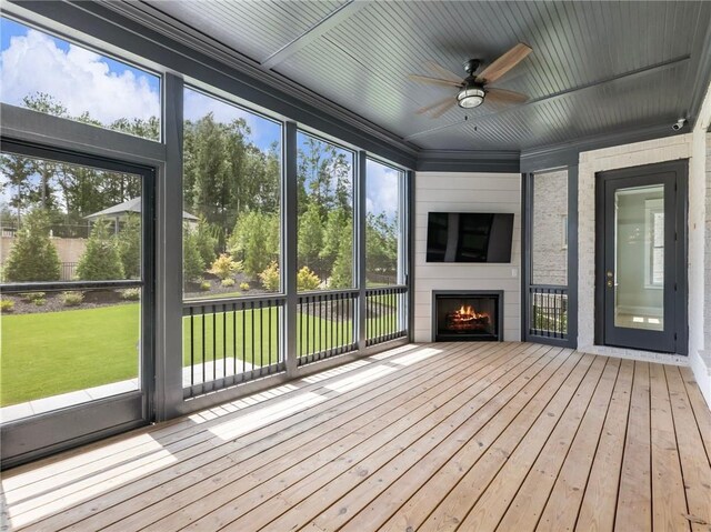 unfurnished sunroom with a large fireplace and ceiling fan