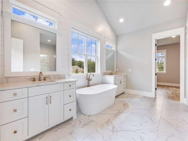 bathroom featuring lofted ceiling, a bathtub, and vanity