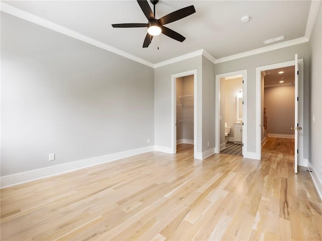 unfurnished bedroom featuring light hardwood / wood-style flooring, ornamental molding, a walk in closet, ensuite bath, and a closet