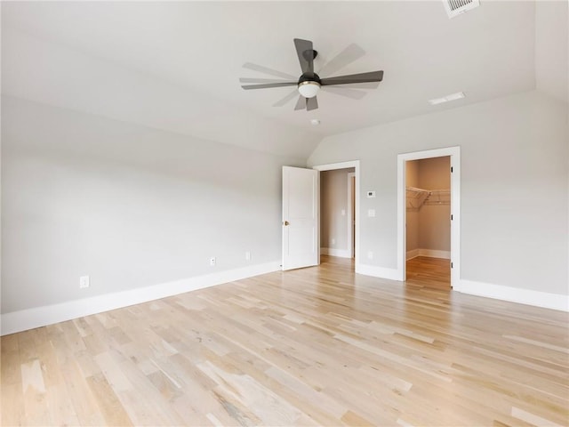 spare room featuring ceiling fan, lofted ceiling, and light wood-type flooring