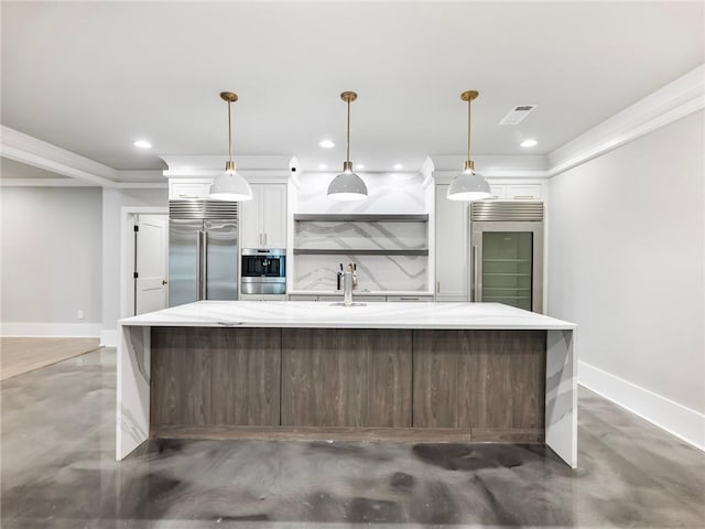 kitchen featuring pendant lighting, stainless steel refrigerator, an island with sink, and stainless steel built in refrigerator