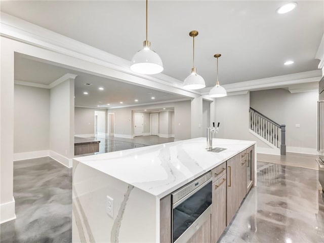 kitchen featuring pendant lighting, a kitchen island with sink, light stone counters, light brown cabinetry, and concrete floors