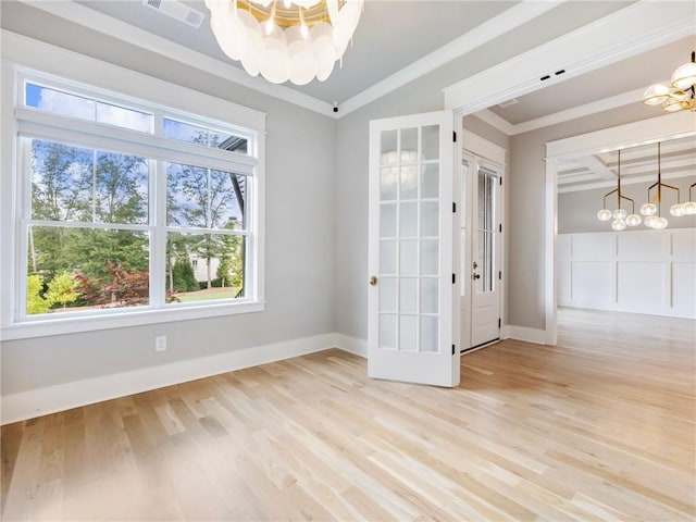 unfurnished room featuring a notable chandelier, light hardwood / wood-style flooring, ornamental molding, and vaulted ceiling