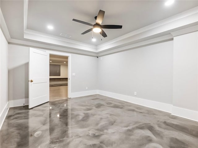 unfurnished bedroom featuring concrete flooring, ornamental molding, ceiling fan, and a tray ceiling