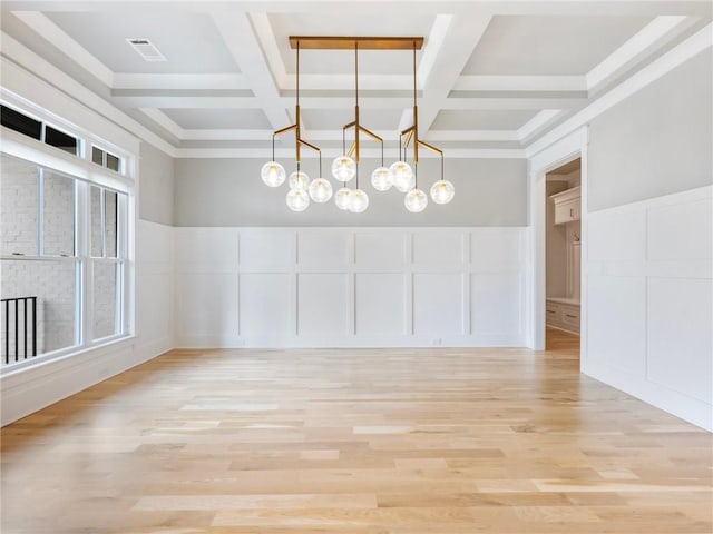 unfurnished dining area featuring beamed ceiling, plenty of natural light, and light hardwood / wood-style floors