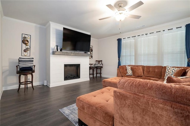 living area with ceiling fan, a large fireplace, dark wood finished floors, and crown molding