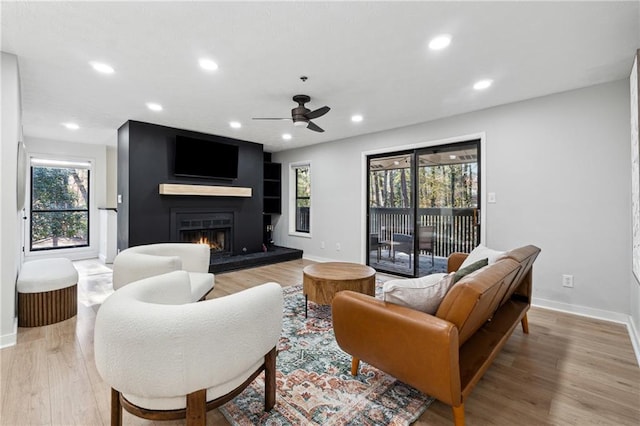 living room featuring ceiling fan, light hardwood / wood-style floors, and a healthy amount of sunlight