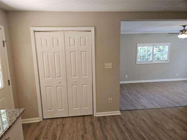 interior space featuring dark wood-style floors, a ceiling fan, and baseboards