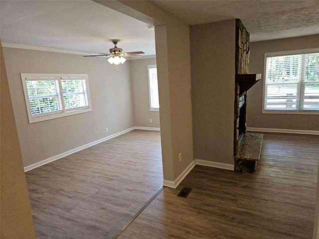 unfurnished living room featuring wood finished floors, visible vents, baseboards, a fireplace with raised hearth, and ceiling fan