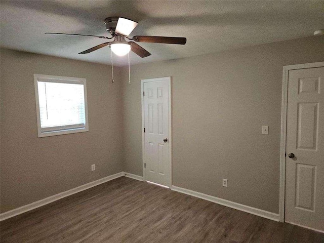 unfurnished bedroom with baseboards, dark wood finished floors, and a ceiling fan