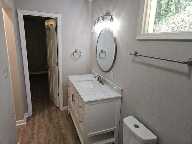 bathroom with baseboards, toilet, wood finished floors, and vanity