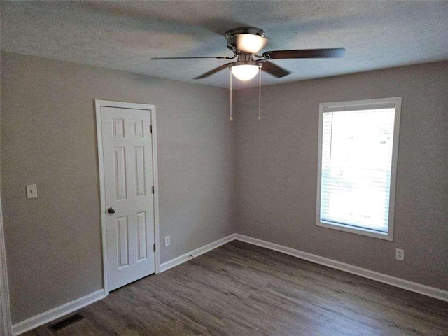 unfurnished bedroom with a ceiling fan, wood finished floors, visible vents, and baseboards