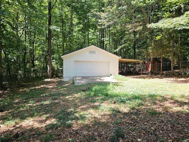 detached garage featuring a wooded view and fence