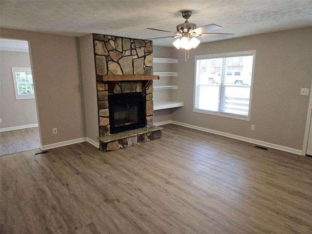 unfurnished living room featuring built in shelves, ceiling fan, baseboards, wood finished floors, and a textured ceiling