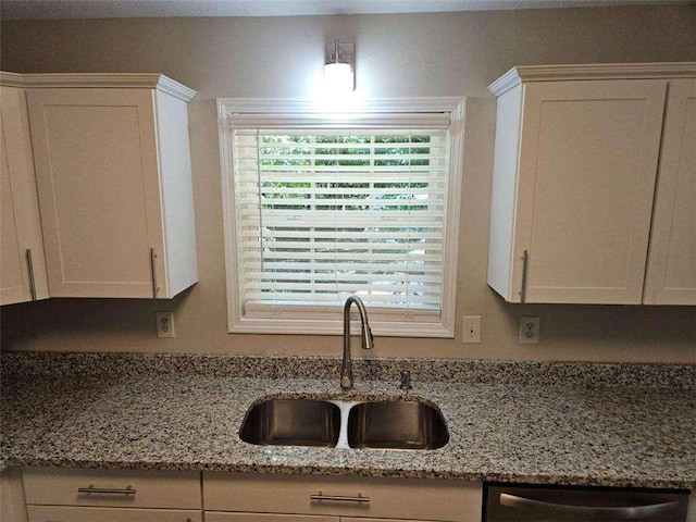 kitchen with a sink, dishwashing machine, light stone counters, and white cabinetry