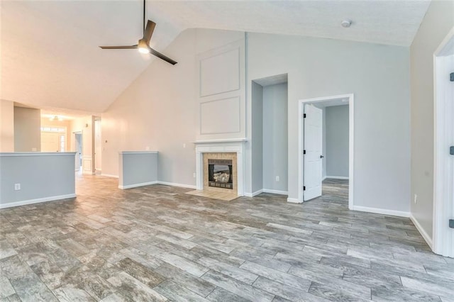 unfurnished living room featuring ceiling fan, a tile fireplace, beam ceiling, and high vaulted ceiling