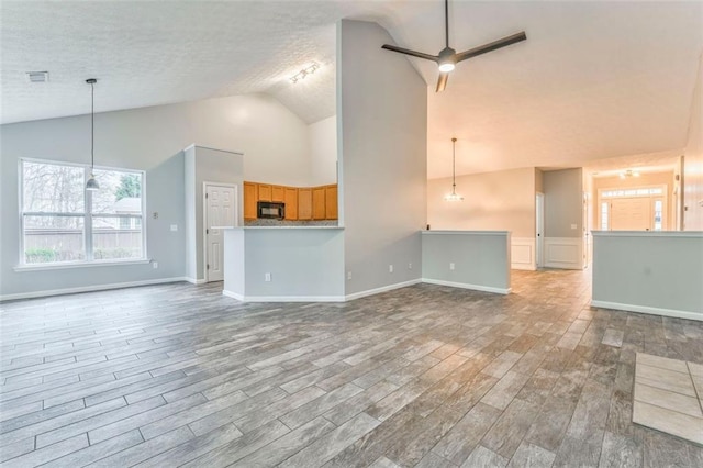 unfurnished living room featuring ceiling fan, a textured ceiling, and lofted ceiling