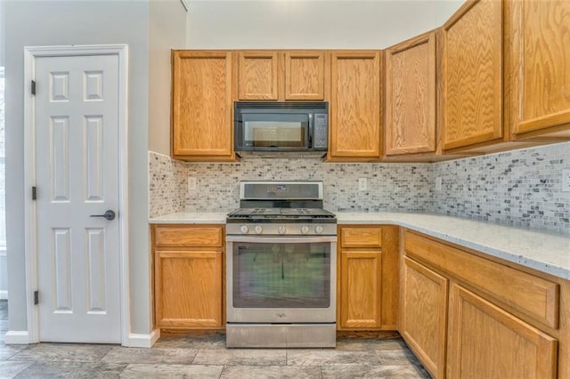 kitchen with stainless steel gas range, light stone countertops, and decorative backsplash