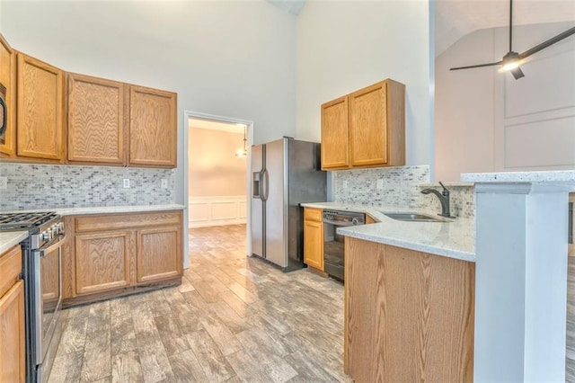 kitchen with ceiling fan, sink, backsplash, high vaulted ceiling, and stainless steel appliances