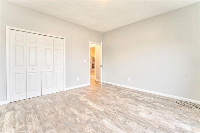 unfurnished bedroom with light hardwood / wood-style floors, a textured ceiling, and a closet